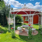 Pavillon Florenz in Sonderfarbe weiss mit Messingkugel und Sonnensegel Weinrot in einem Garten