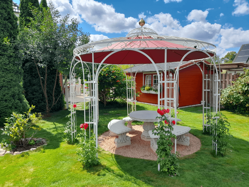 Pavillon Florenz in Sonderfarbe weiss mit Messingkugel und Sonnensegel Weinrot in einem Garten