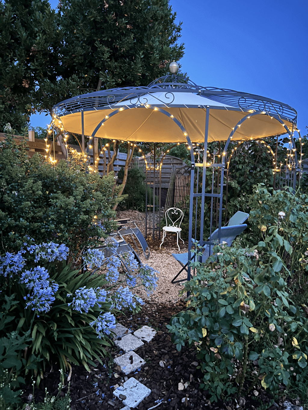 Pavillon Florenz pulverbeschichtet anthrazit mit Messingkugel und Sonnensegel mit Lichterkette in einem Garten