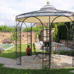 Pavillon Florenz mit Messingkugel und Sonnensegel in pulverbeschichteter Ausführung in einem schönen Garten mit Pool