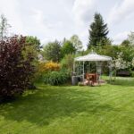 Pavillon Florenz mit Sonnensegel und Messingkugel in feurverzinkter Ausführung im schönen Garten mit Sitzgelegenheiten