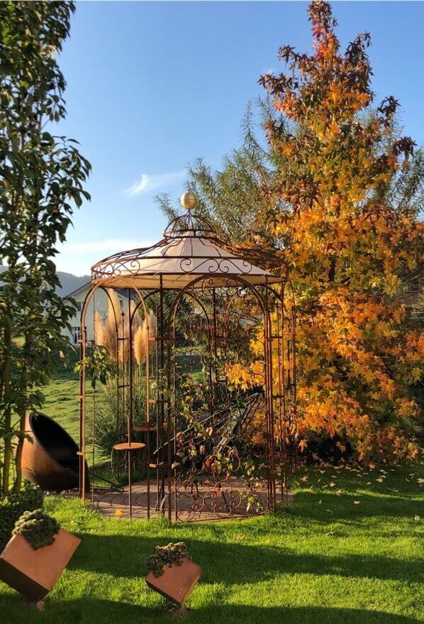 'Gartenpavillon Siena mit Messingkugel und Sonnensegel in unbeschichteter Ausführung mit herbstlichen Bäumen'