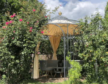 Pavillon Milano in pulverbeschichtet anthrazit mit Sitzmoebeln in einem bepflanzen Garten