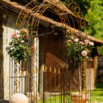 Rosenbogen Calabria in unbeschichteter Ausführung mit einem Tür und mit Rosen verziert