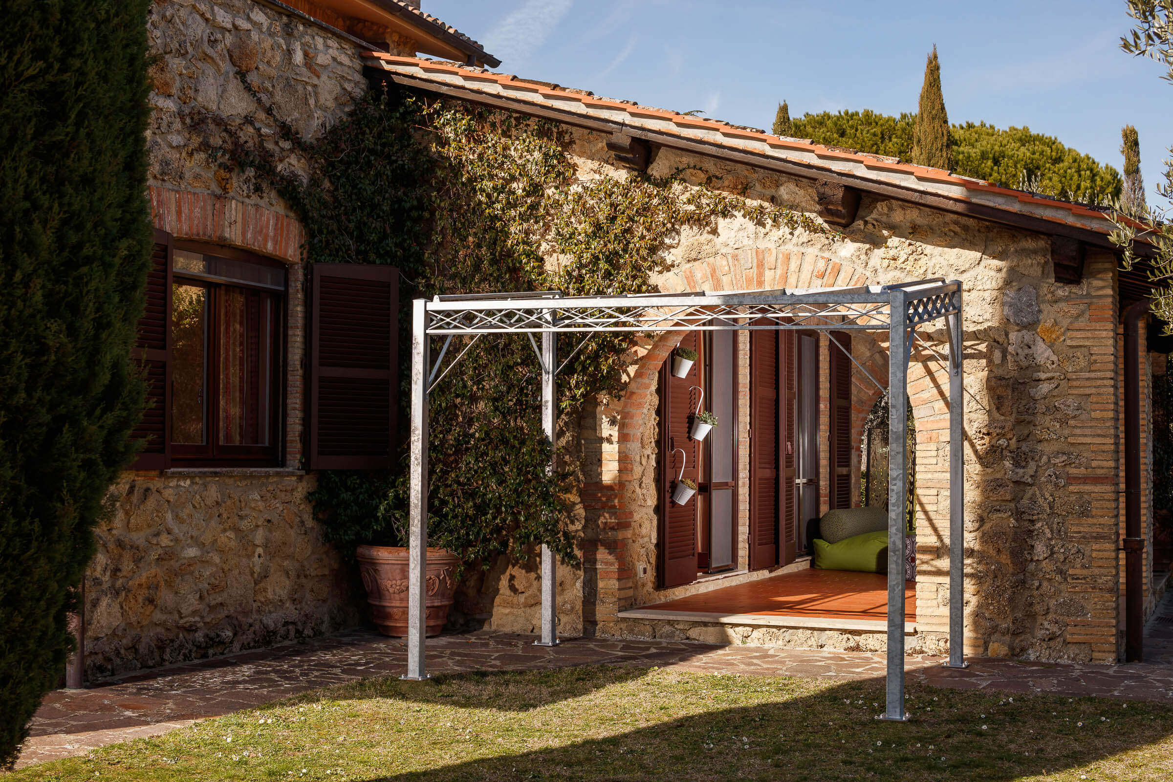 Pergola Ischia in feuerverzinkter Ausführung an einer terrasse angelehnt